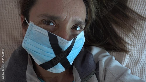 4K Lockdown isolation period - Close up face of woman in mask on bed protecting against lockdown
 photo