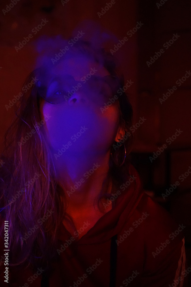 Close up vertical portrait of vaping girl in neon blue light Close up vertical portrait of vaping girl in neon blue light