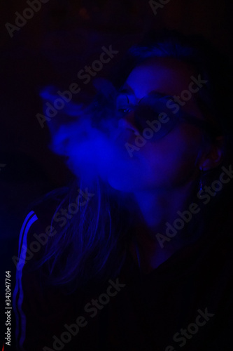 Close up vertical portrait of vaping girl in neon blue light
