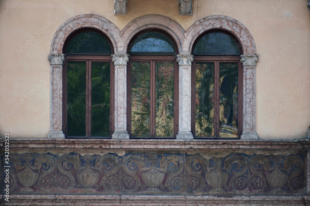 Italian windows on the beige wall facade with the pattern under them