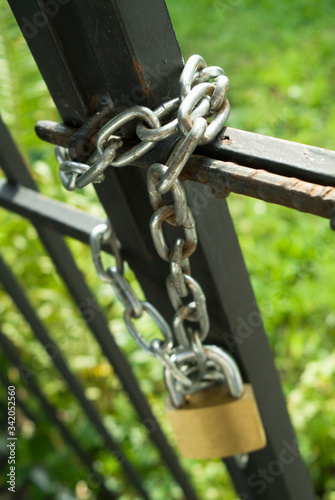 A metal gate closed and secured with a chain and a padlock.