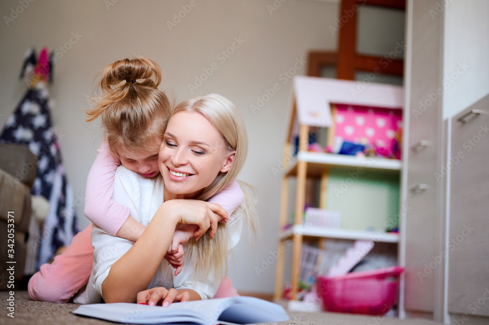 Young mother is relaxing and having fun at home with her daughter, a woman is reading a book to her child, a strong family, love, concept. Young mother is relaxing and having fun at home with her daughter, a woman is reading a book to her child, a strong family, love, concept.