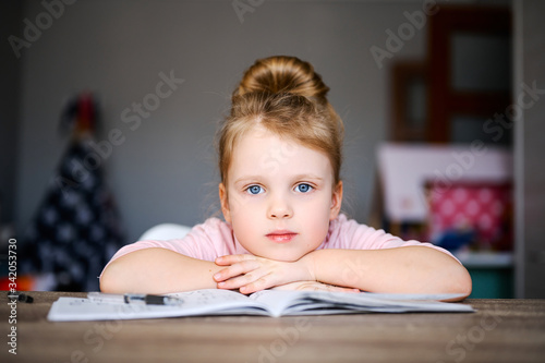 Cute little caucasian preschool girl doing homework. Child reading books and learning at home. Distance education