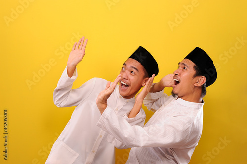 Another pose of Two handsome happy Asian Muslim with satisfied amazed face while showing winning gesture