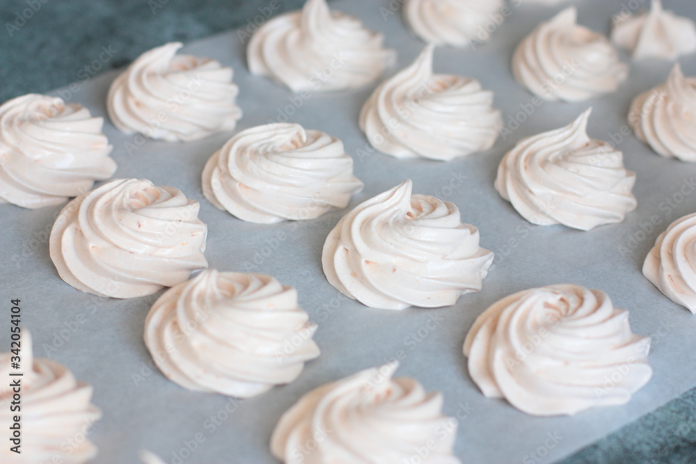 Many fresh (just made) marshmallow roses (zephyrs) in lines on cooking paper Many fresh (just made) marshmallow roses (zephyrs) in lines on cooking paper