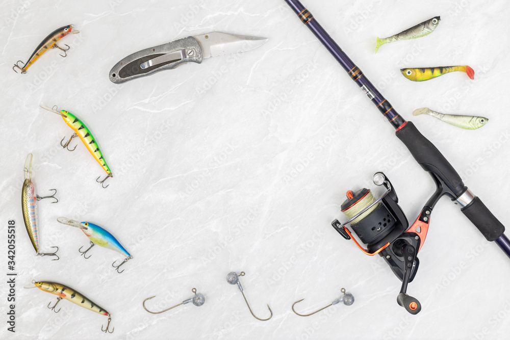 Fishing rod with a reel and colorful fishing lures with knife above white background Fishing rod with a reel and colorful fishing lures with knife above white background
