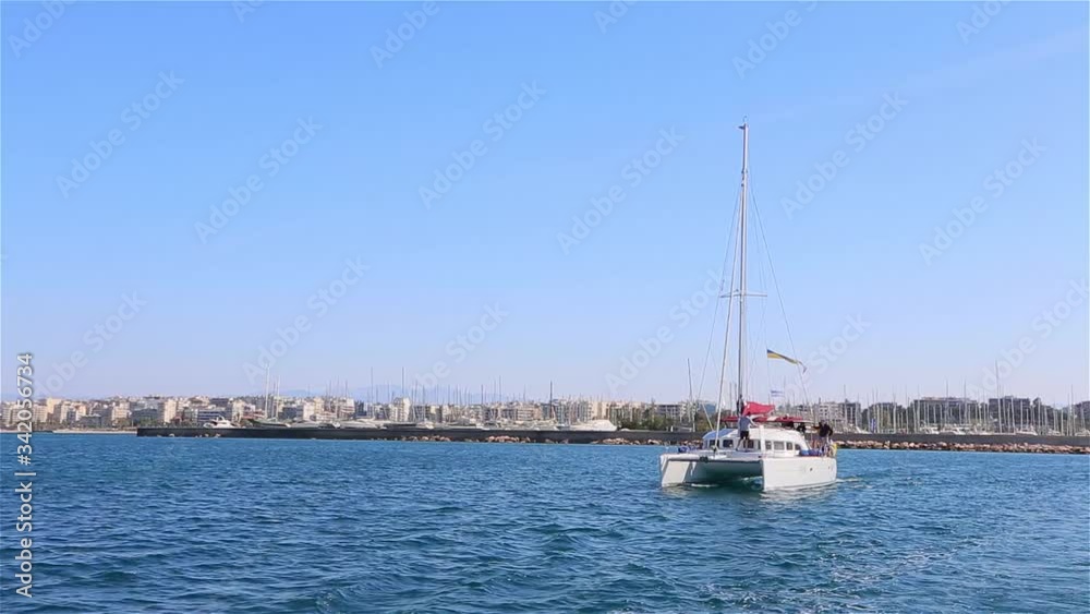 white catamaran emerges from the marina against the background of the city of Athens, Greece, crisis in Greece, yacht trip, sea ped Athens white catamaran emerges from the marina against the background of the city of Athens, Greece, crisis in Greece, yacht trip, sea ped Athens