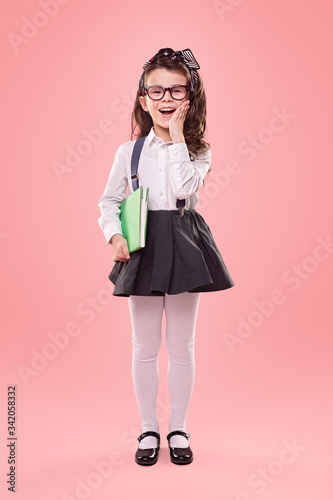 Surprised little school girl on pink background