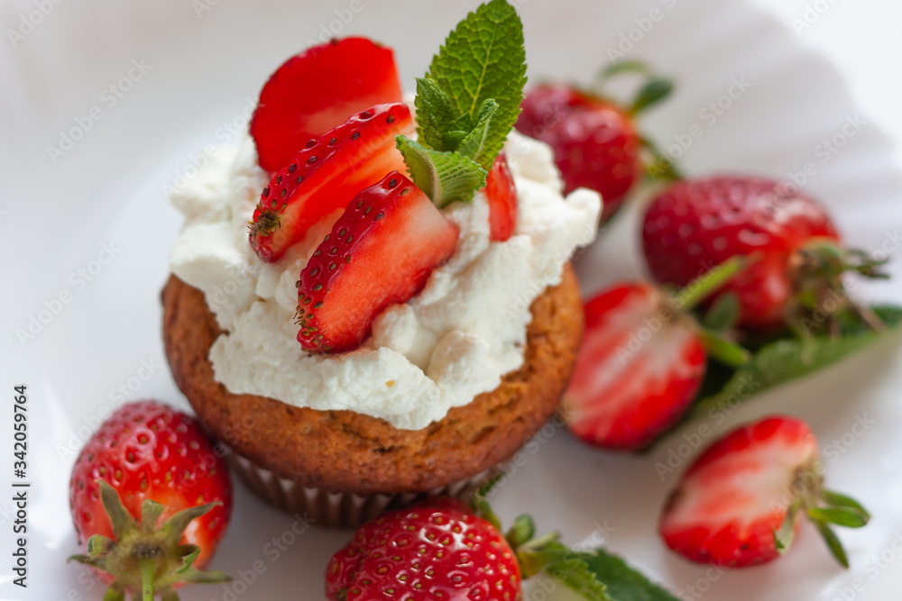 Homemade muffins with fresh strawberries on white plate. Homemade tasty dessert or breakfast. Healthy eating concept Homemade muffins with fresh strawberries on white plate. Homemade tasty dessert or breakfast. Healthy eating concept