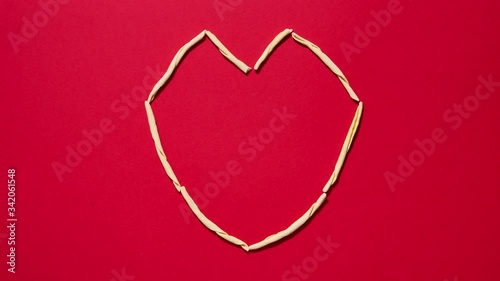 Italian fileja pasta on red background shaped as a heart in a heartbeat animation. Concept for food love and pleasure. 4K stop motion seamless loop
