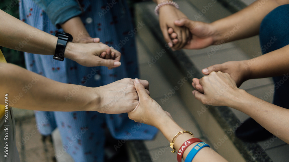 Group of christian are holding hands and pray together outdoor.