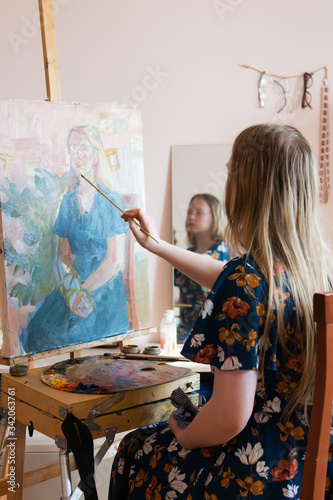 teen girl at home paints, looking in the mirror