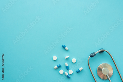Pharmaceutical medicine tablets and stethoscope on a blue background. Face mask, surgical mask. The concept of medicine, hygiene and healthcare. Coronavirus. top view, copy space. Flu season.