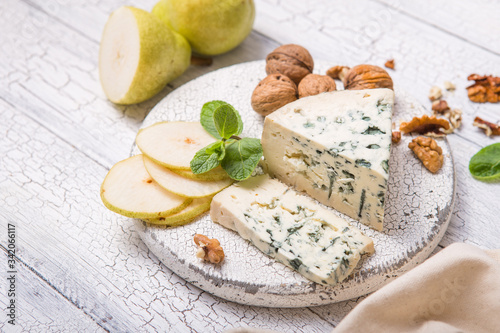 Segment of blue mould cheese - Gorgonzola with pear and walnuts on wooden board. Top view