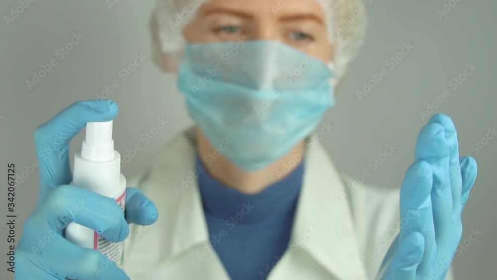 Medicine woman in disposable gloves is spraying antiseptic on hands in gloves. Medicine woman in disposable gloves is spraying antiseptic on hands in gloves.