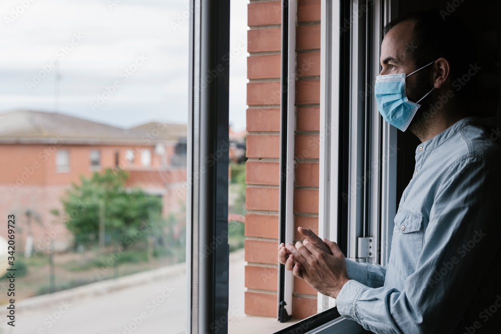Man in quarantine at home for coronavirus is wearing protective mask is clapping people who are fighting against covid19 Man in quarantine at home for coronavirus is wearing protective mask is clapping people who are fighting against covid19