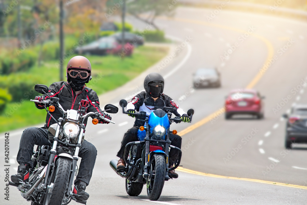 Two young biker riding motorcycles on curved road