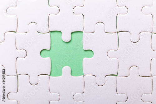 White puzzle background with one piece missing. Close-up. Concept success of business © lizaelesina
