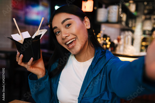 Fotografie Photo of asian woman holding chinese noodles while taking selfie photo