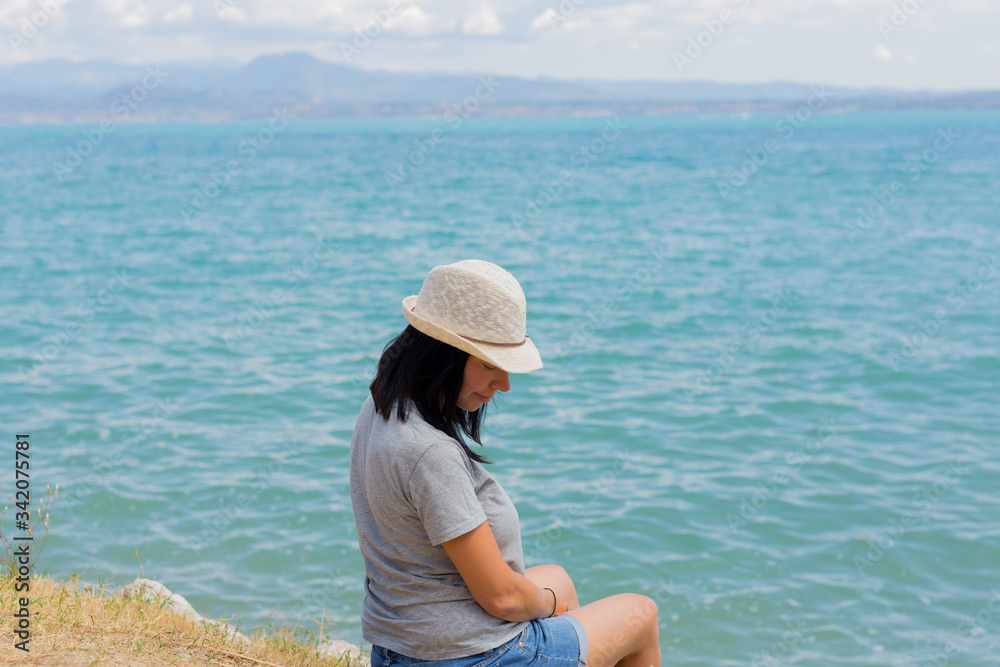 Beautiful lifestyle woman sitting and relaxing on the shore of lake contemplating amazing landscape. Family summer vacation. Relax. Happiness. Pregnant fat woman. Copy space. Beautiful lifestyle woman sitting and relaxing on the shore of lake contemplating amazing landscape. Family summer vacation. Relax. Happiness. Pregnant fat woman. Copy space.