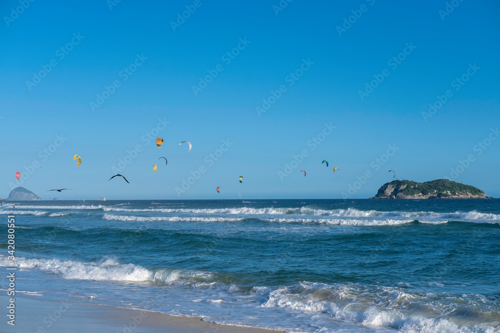 Kitesurfing in the ocean on Rio de Janeiro sandy beach in Brasil in a sunny day.