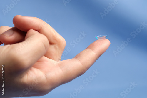 Contact lenses on the fingertip on a blue background, space for text