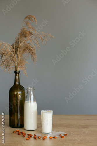 High angle view almond and milk in white bowl on wooden textured background. Various vegan plant based milk and ingredients , top view, copy space. Dairy free milk substitute drink, healthy eating