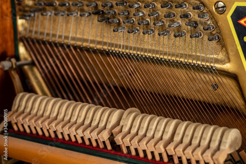 Open upright piano mechanism with strings and hammers. Selective focus.