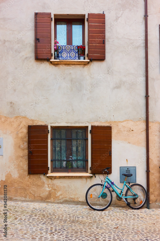 Bicycle in the street near wall of old house Bicycle in the street near wall of old house