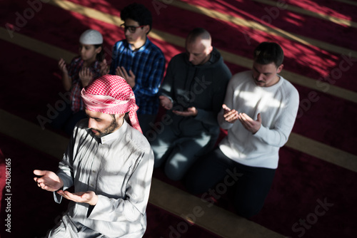 Group of young Muslim people praying. Muslim prayers doing a pray inside the mosque.