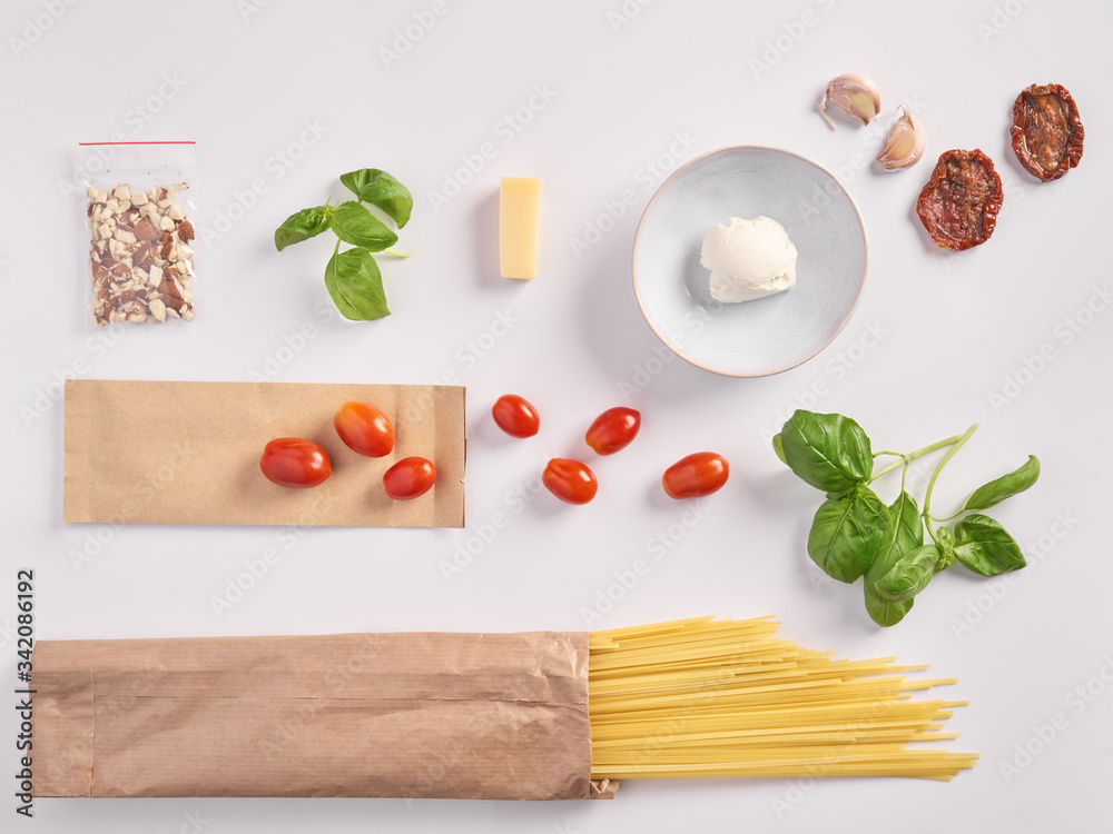 A set of products for an Italian dinner: spaghetti pasta, cherry tomatoes, basil, garlic, cream cheese on a white background. Dinner Set Food Delivery