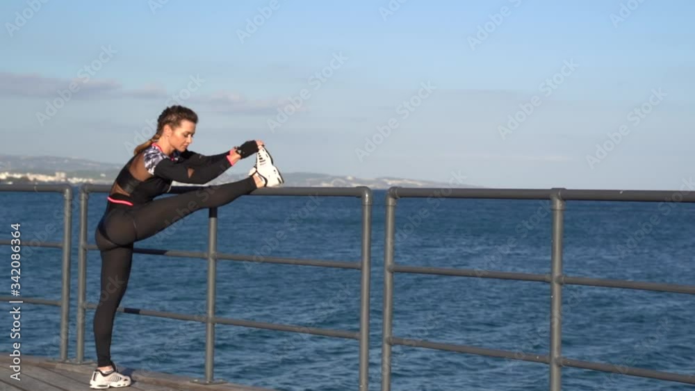 Caucasian female fitness model stretching outdoor at a sea promenade gimbal shot Caucasian female fitness model stretching outdoor at a sea promenade gimbal shot