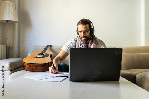 Contemporary man with guitar writing chords in living room