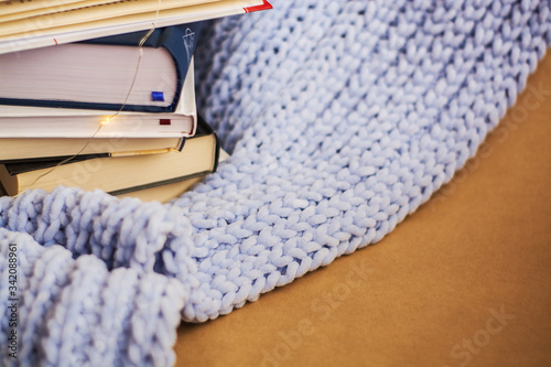 Home cozy place work and study. Stack of books on blue knitted plaid.