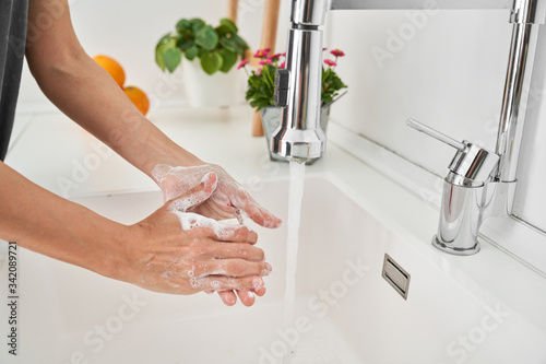 Woman washing her hands on the kitchen sink to avoid possible infection photo