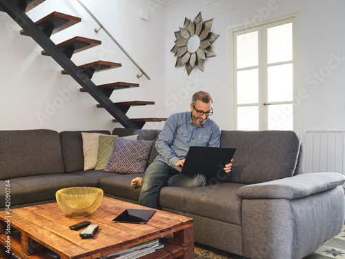 Man working on laptop alone on sofa in living room at home