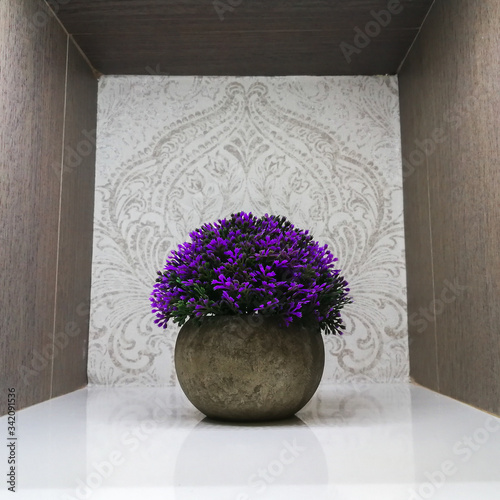 planta con flores artificiales sobre hornacina de madera