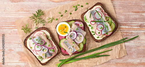 Smorrebrod traditional Danish sandwiches fish, radish, mayonnaise. Open sandwich with rye bread, herring on wooden background, top view. Tasty fish smorrebrod. Flat lay