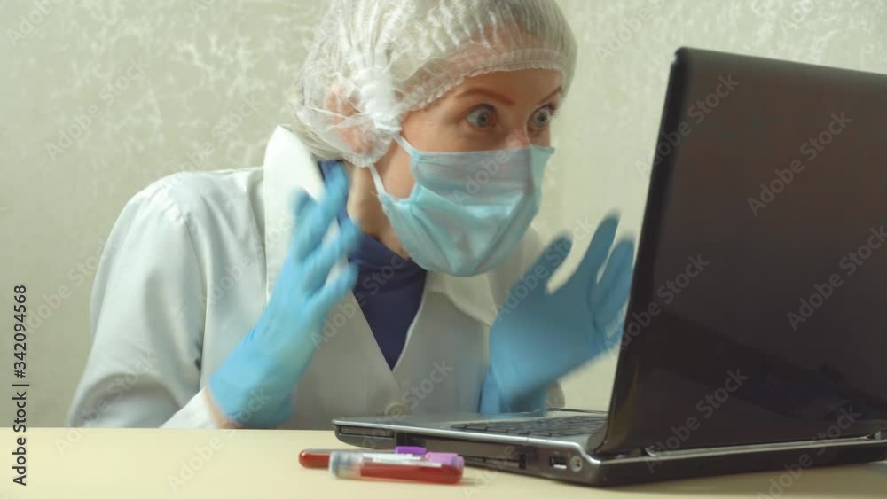 Portrait of a young woman doctor, she is looking into a laptop monitor and is shocked. Portrait of a young woman doctor, she is looking into a laptop monitor and is shocked.