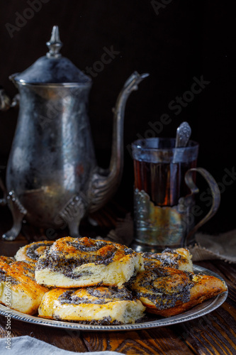 homemade rolls with poppy seeds and hot tea on wooden background