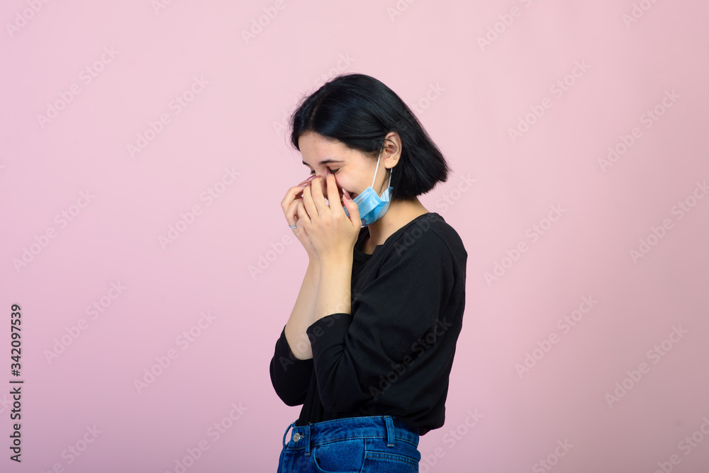 The caucasian girl in blue colored protective face mask. The girl looking at camera. Portrait shot over pink background. virus and pollution protection concept. The caucasian girl in blue colored protective face mask. The girl looking at camera. Portrait shot over pink background. virus and pollution protection concept.