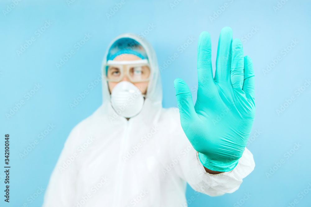 portrait of tired doctor after shift in the hospital. The doctor in protective clothing - glasses, mask, gloves on blue background. The doctor treating patients with coronavirus. Covid-2019 portrait of tired doctor after shift in the hospital. The doctor in protective clothing - glasses, mask, gloves on blue background. The doctor treating patients with coronavirus. Covid-2019