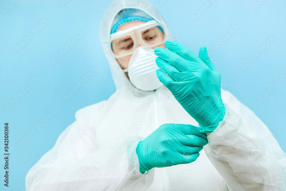 close-up portrait of tired doctor after shift in the hospital. The doctor in protective clothing - glasses, mask, gloves on white background. The doctor treating patients with coronavirus. Covid-2019 close-up portrait of tired doctor after shift in the hospital. The doctor in protective clothing - glasses, mask, gloves on white background. The doctor treating patients with coronavirus. Covid-2019