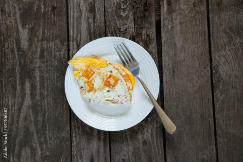 fried egg on a white plate on an old wooden table photo