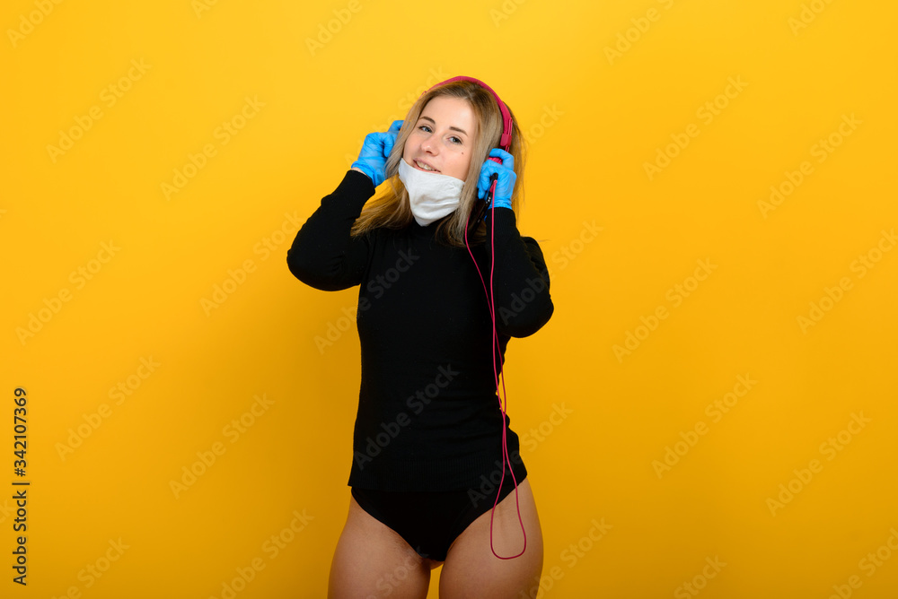 Portrait of a girl in a medical mask, which puts on a rubber glove. Yellow and grey background. Copy space. Portrait of a girl in a medical mask, which puts on a rubber glove. Yellow and grey background. Copy space.