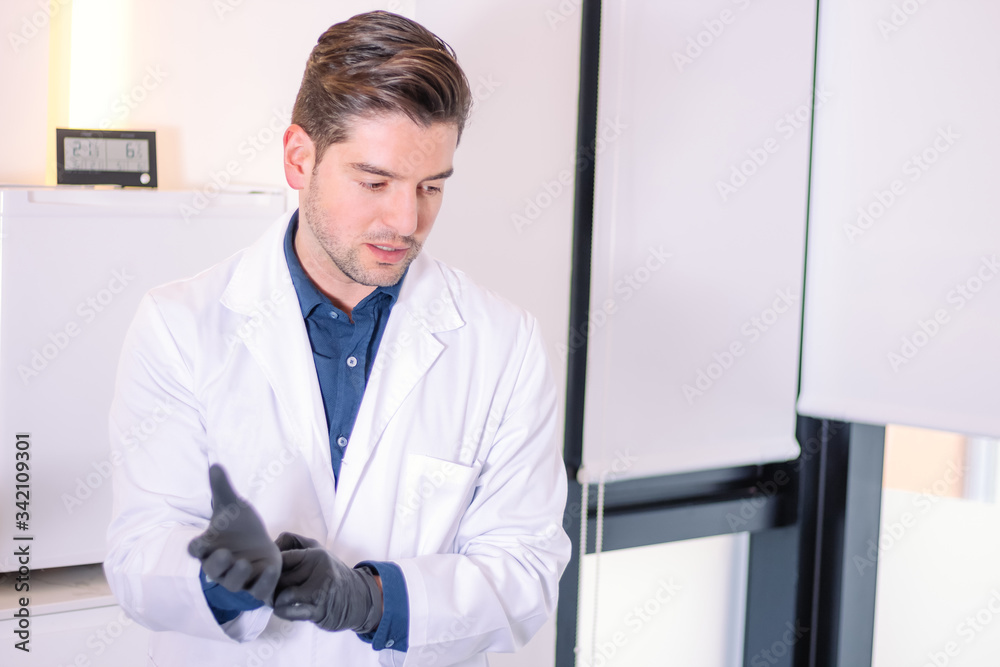 Young male doctor putting on gloves