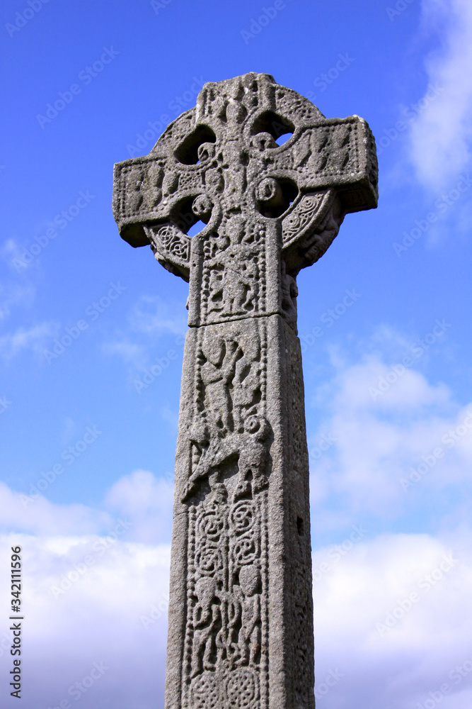 Celtic cross in an Irish cemetery with blue sky
