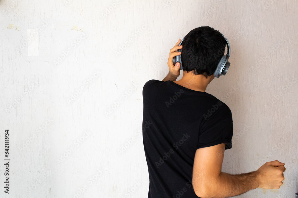 Young Hispanic man with black clothes dancing with headphones on his head on a white background Young Hispanic man with black clothes dancing with headphones on his head on a white background