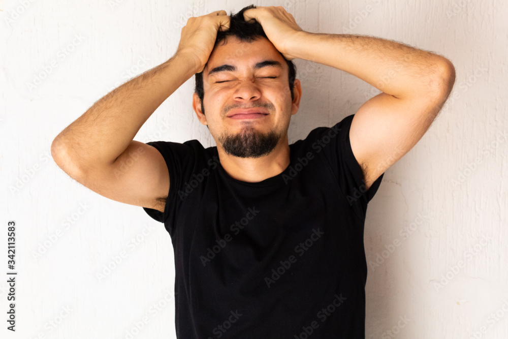Young short-haired Hispanic man with black clothes, angry, furious, upset, stressed posing on a white background Young short-haired Hispanic man with black clothes, angry, furious, upset, stressed posing on a white background