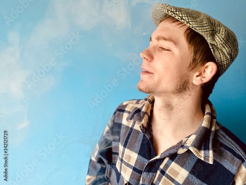 a young  man in checked shirt and retro hat smoking electronic cigarette photo